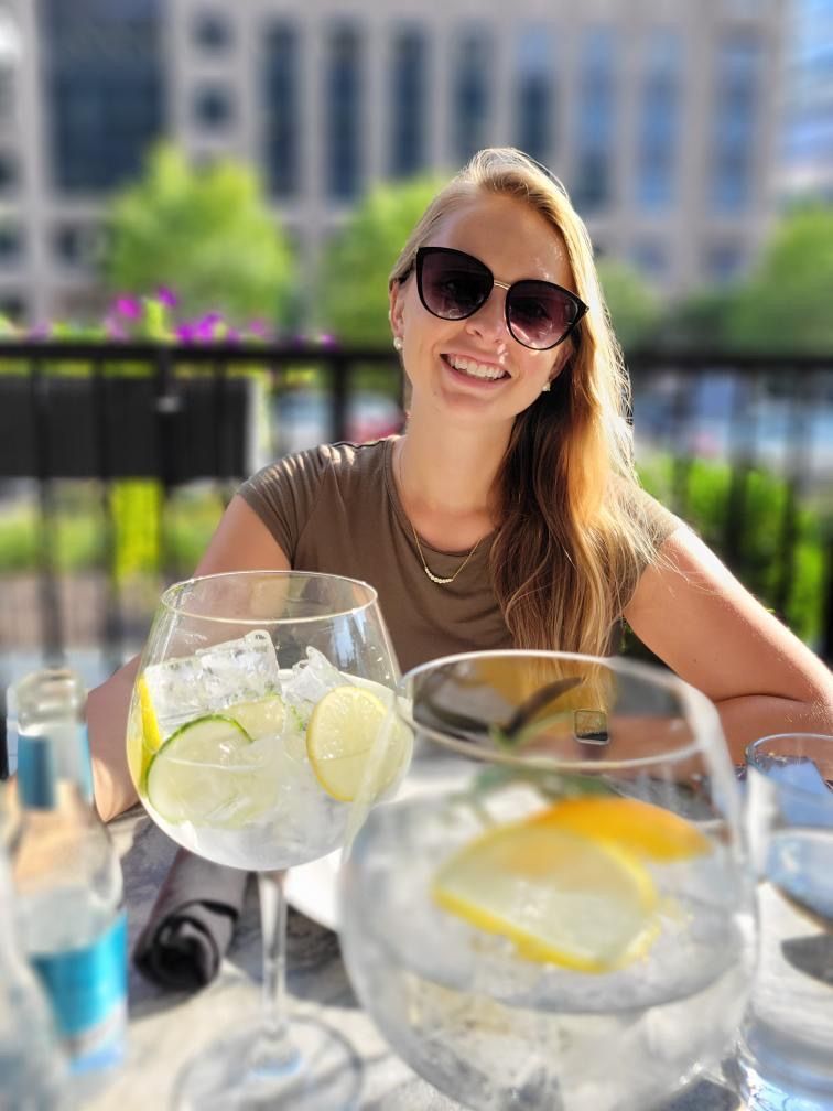 Berenice smiling at an outdoor table with gin and tonics