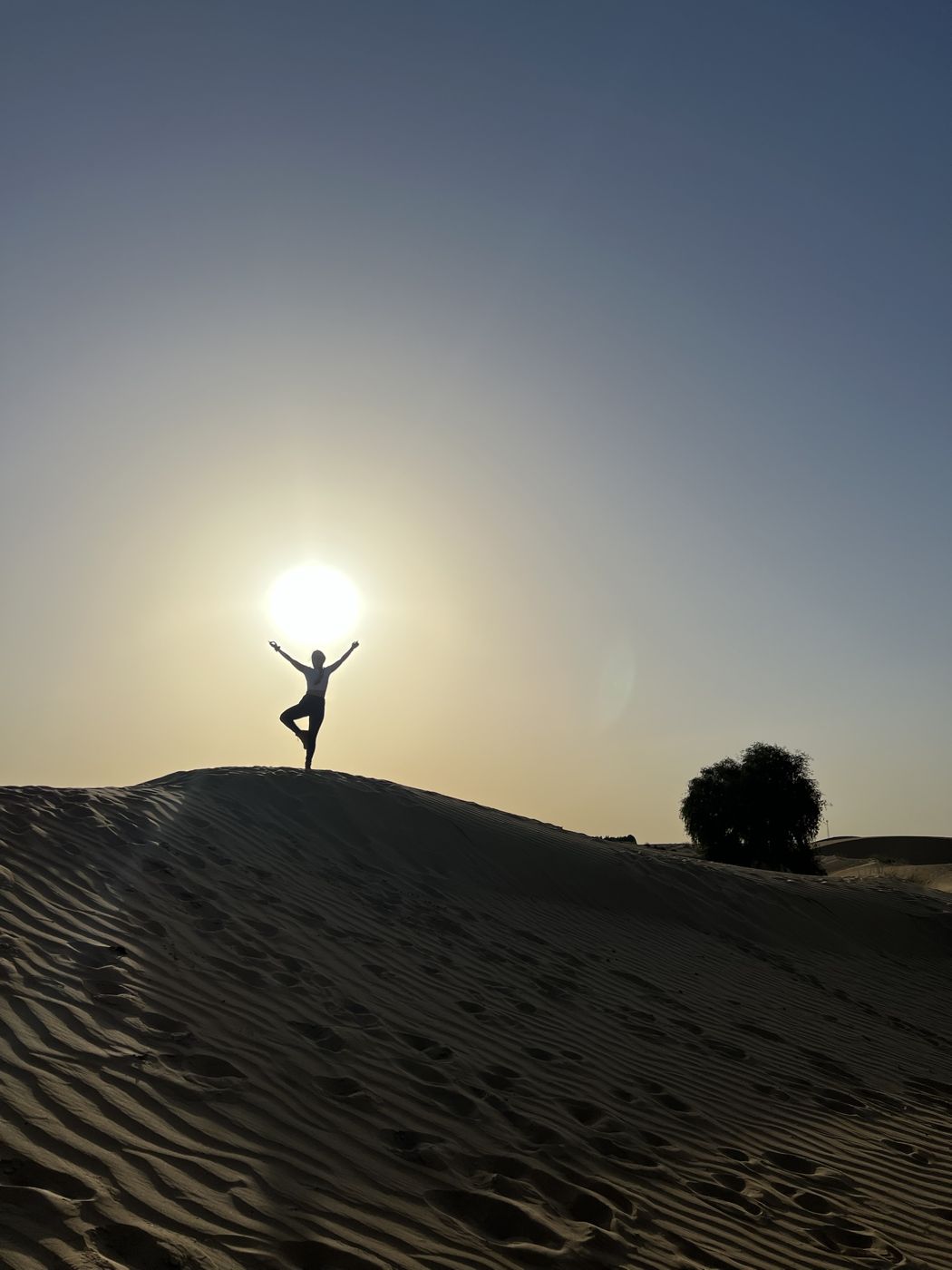 Berenice in a yoga pose on a desert dune at sunset
