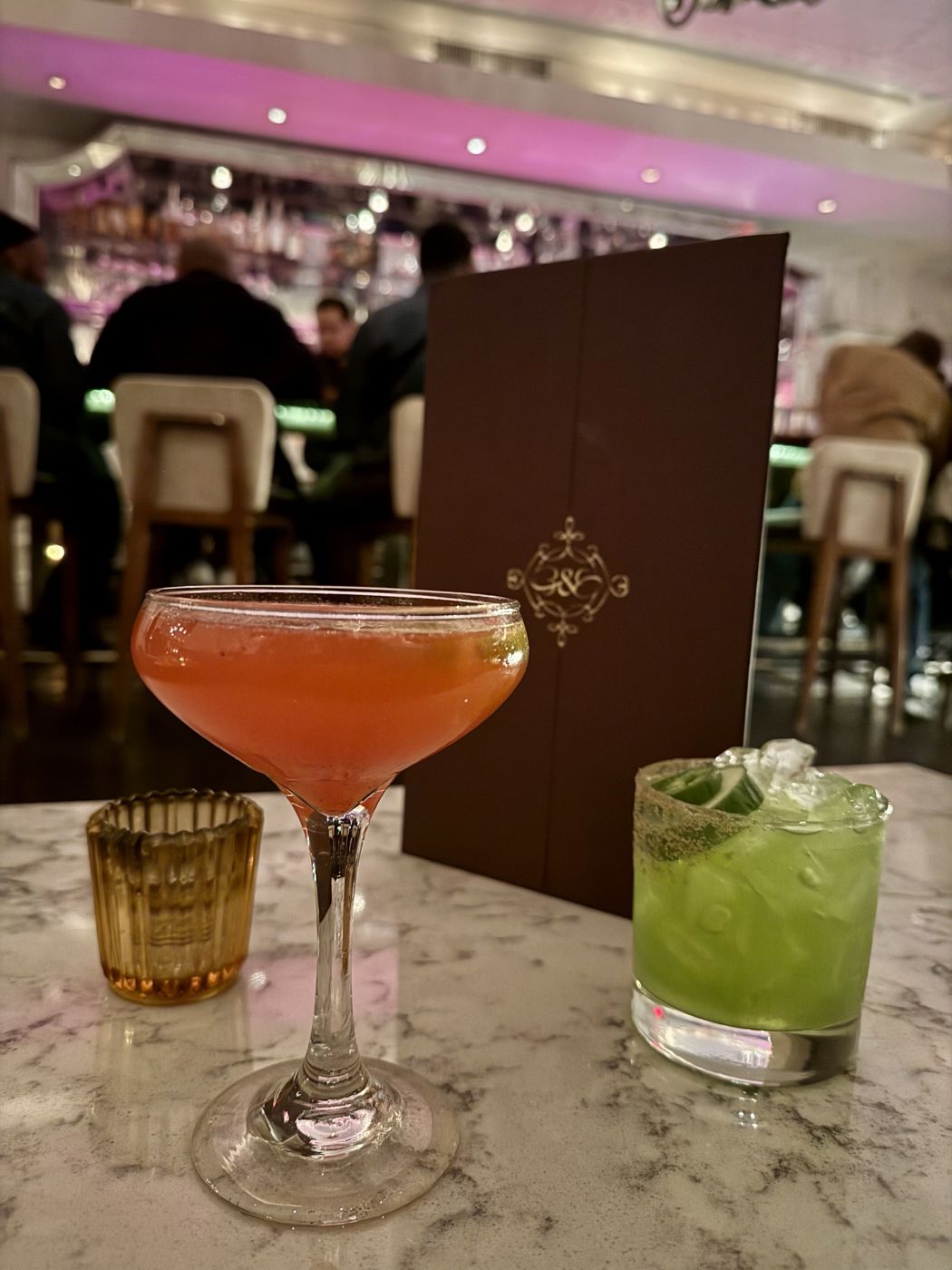 Two cocktails at a pink-lit bar
